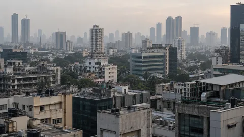 The Mumbai skyline by day, mid-rise blocks in the foreground and towers behind them in the haze.