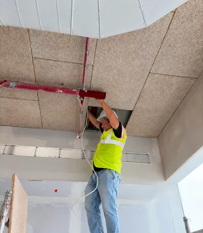 A Concept engineer fixing a detector to a ceiling on a live site.
